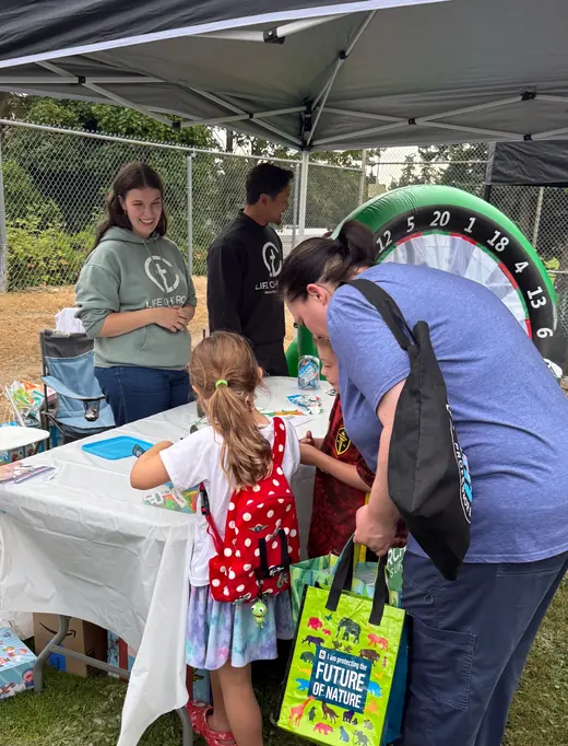 Life 425.Church volunteers welcoming families at a community activity table